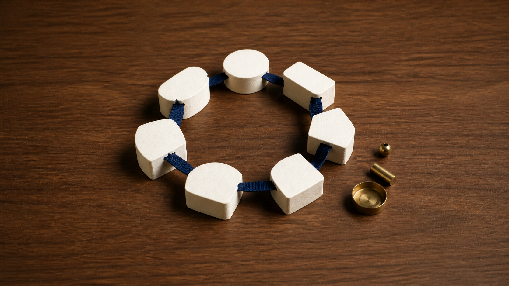 Cream organisational elements connected by a navy fabric band, with decorative brass objects sitting separately